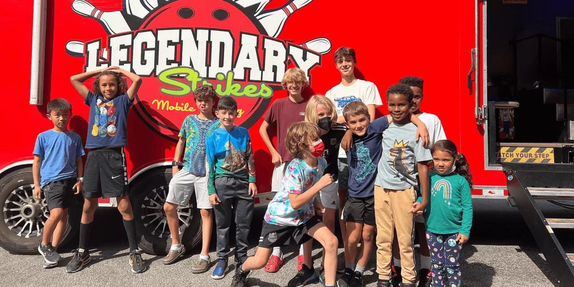Real guests posing in front of the Legendary Strikes mobile bowling truck and game truck trailer in Atlanta, Georgia